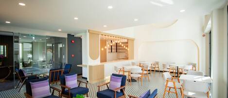 A modern lounge area with seating arrangements, a central bar area, and a patterned floor.