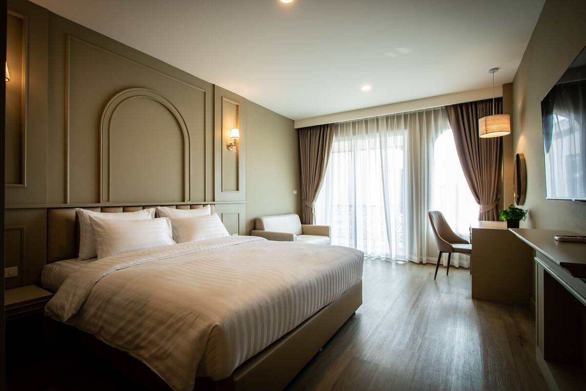 A modern hotel room with a large bed, a desk, and a chair.