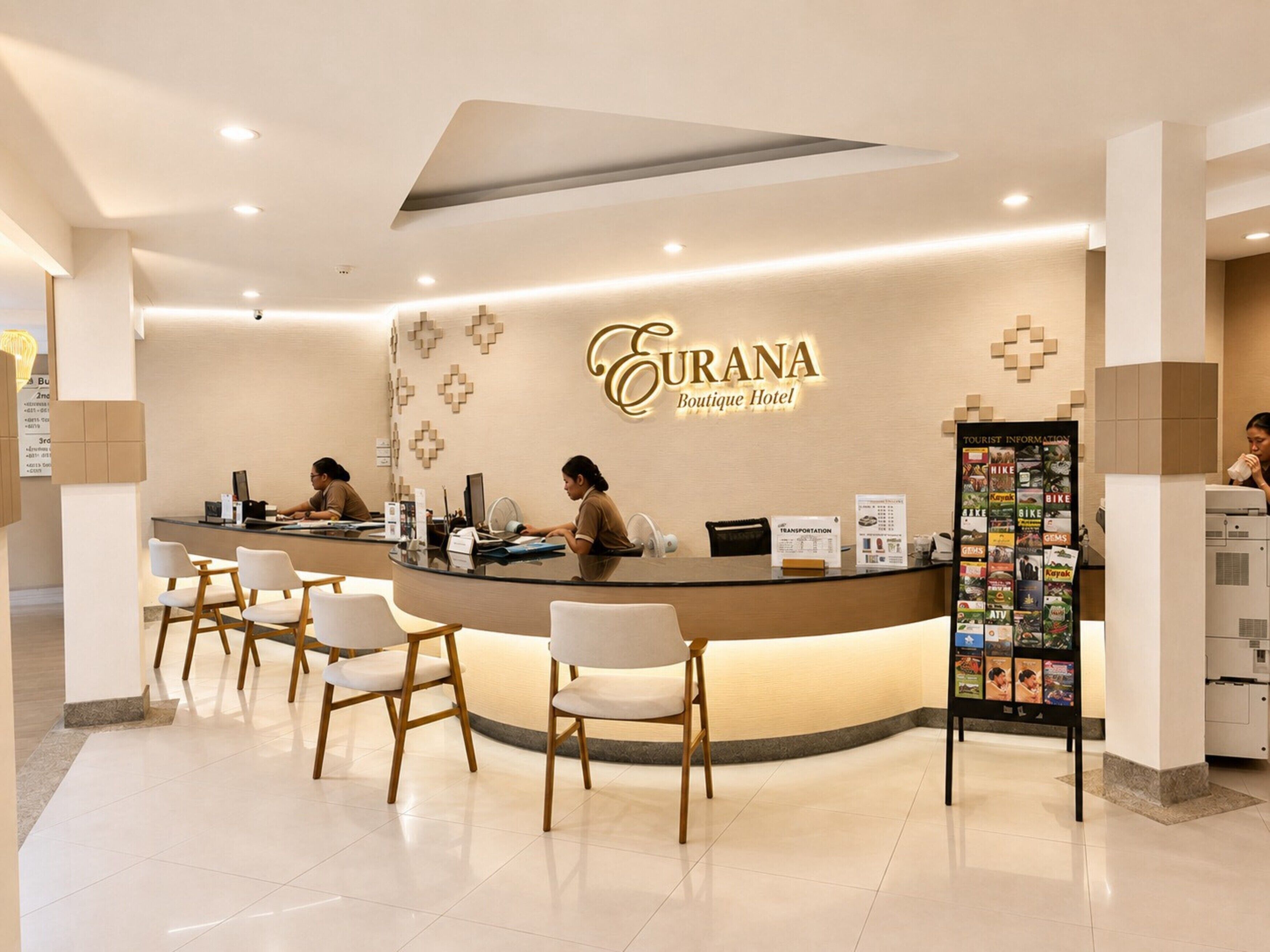 A hotel reception desk with a modern design, a sign for the boutique hotel, and a tourist information board.
