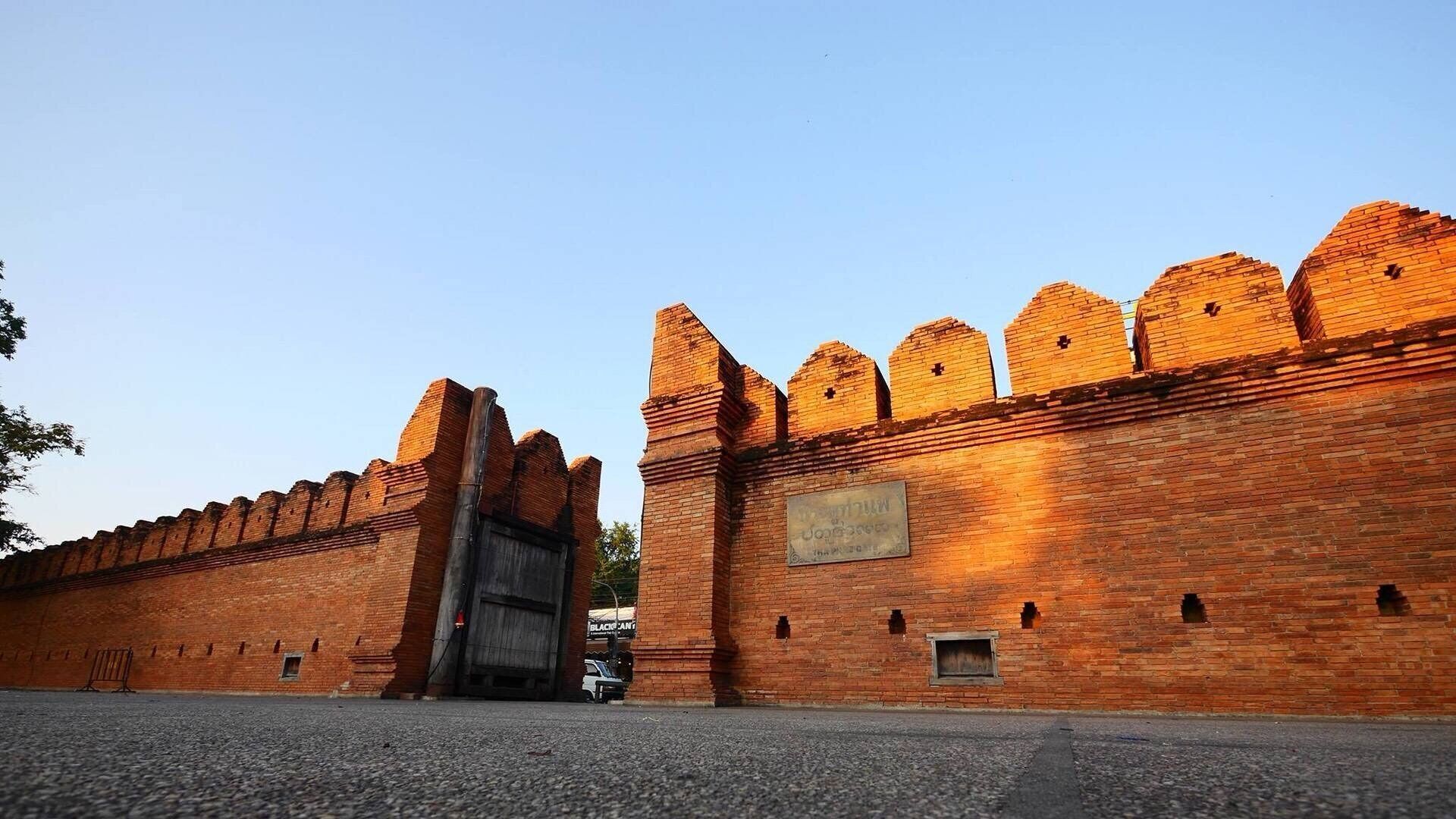 A brick wall with a gate and a sign.