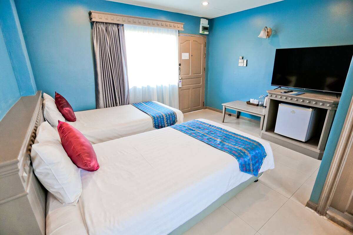 A hotel room with two beds, a TV, a small table, and a wardrobe.