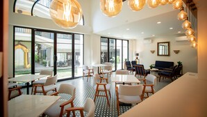 A spacious dining area with large windows, modern furniture, and hanging light fixtures.
