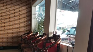 A restaurant interior with brick walls, large windows, and a row of wooden chairs. - Dara Reang Sey Hotel Phnom Penh (Phnom Penh)