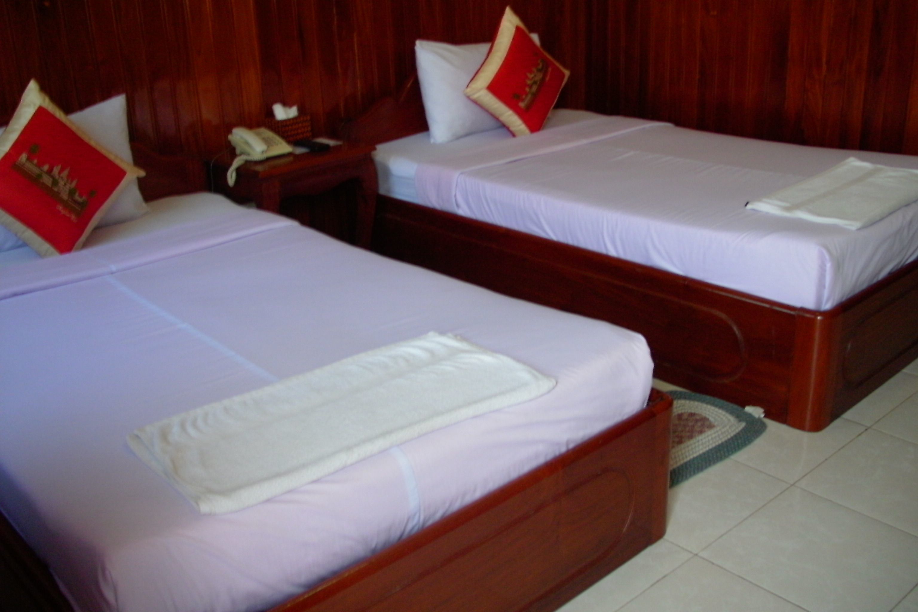 Two single beds with wooden headboards and white linens.