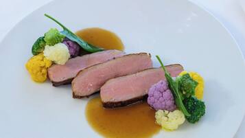 Ein Teller mit geschnittenem Fleisch, Blumenkohl und Soße.