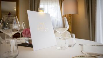 A table set for a meal with a menu, wine glasses, and a vase of flowers.