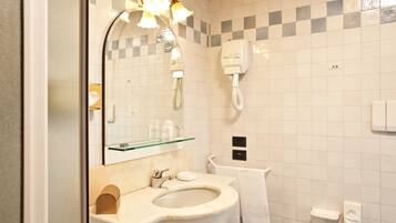 Un baño con lavabo, espejo, toallero y un teléfono instalado en la pared.
