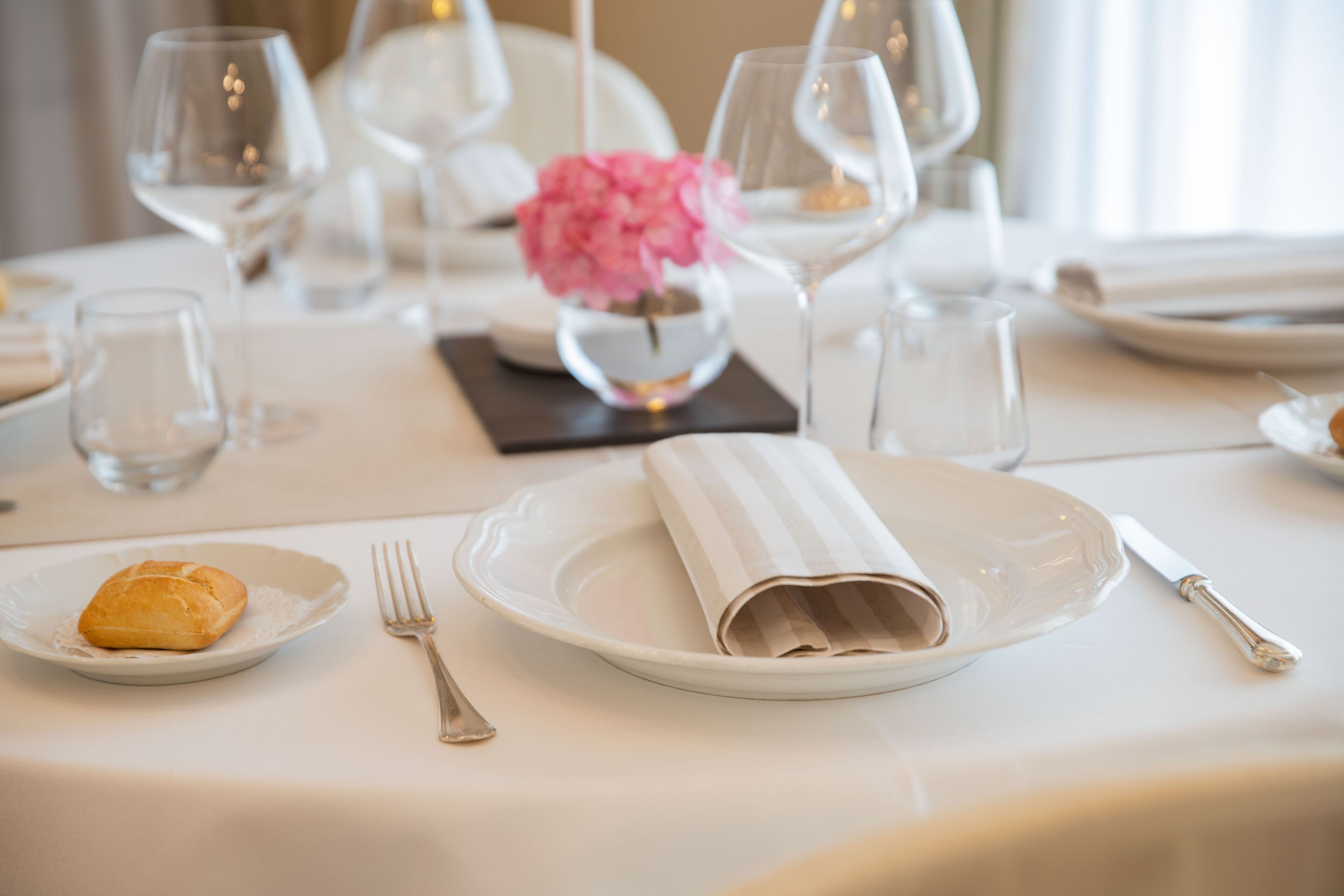 A table set for a meal with plates, cutlery, and a vase with flowers.
