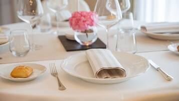 Une table mise pour un repas, avec des assiettes, des couverts et un vase rempli de fleurs.