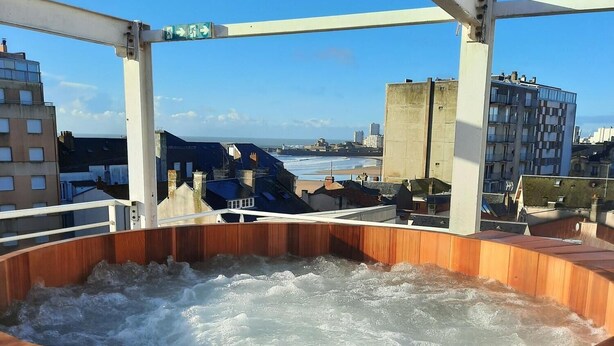 A wooden hot tub with a view of the city and ocean. -  Hôtel Arc en Ciel et SPA - Les Sables d'Olonne (Les Sables-d'Olonne)