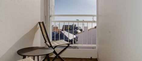 A balcony with a white railing, a small table, and two chairs.