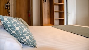 A bedroom with a bed, pillows, a wardrobe, and a closet. -  Hôtel Arc en Ciel et SPA - Les Sables d'Olonne (Les Sables-d'Olonne)