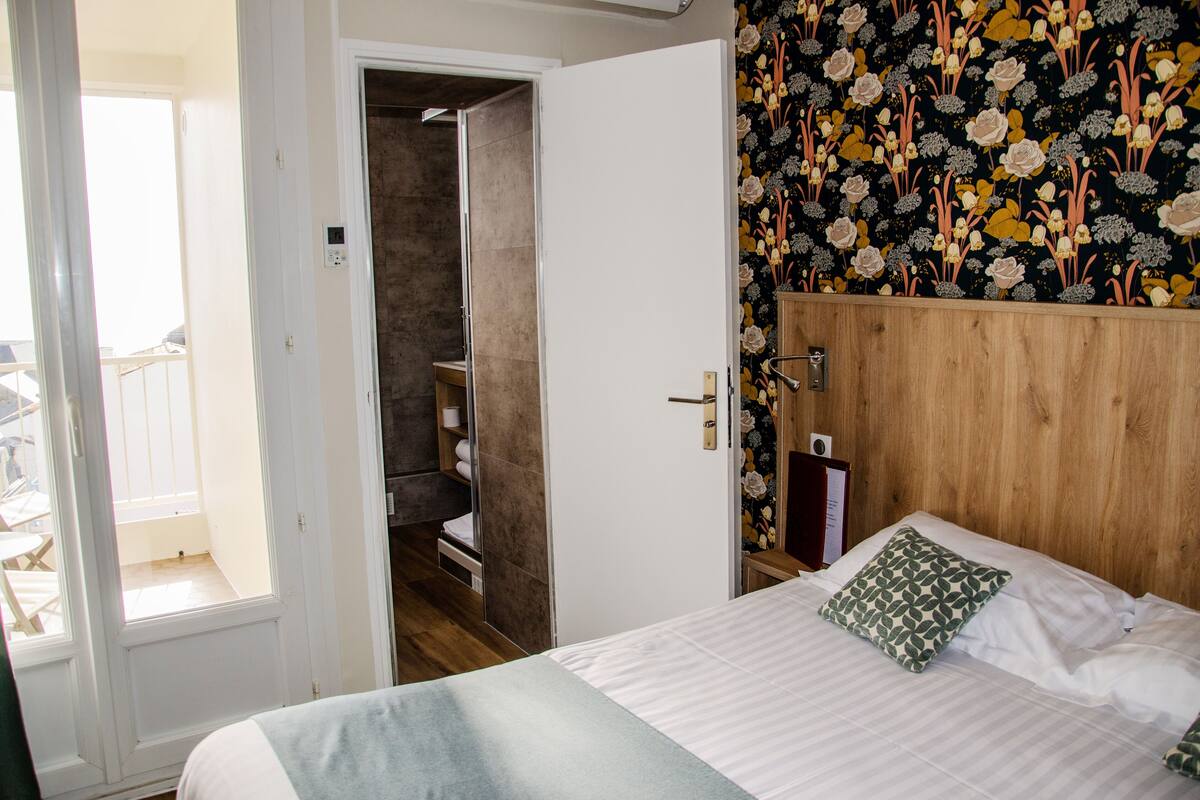 Ein Schlafzimmer mit Bett, Holz-Kopfteil, Kleiderschrank und einem Badezimmer mit Dusche.