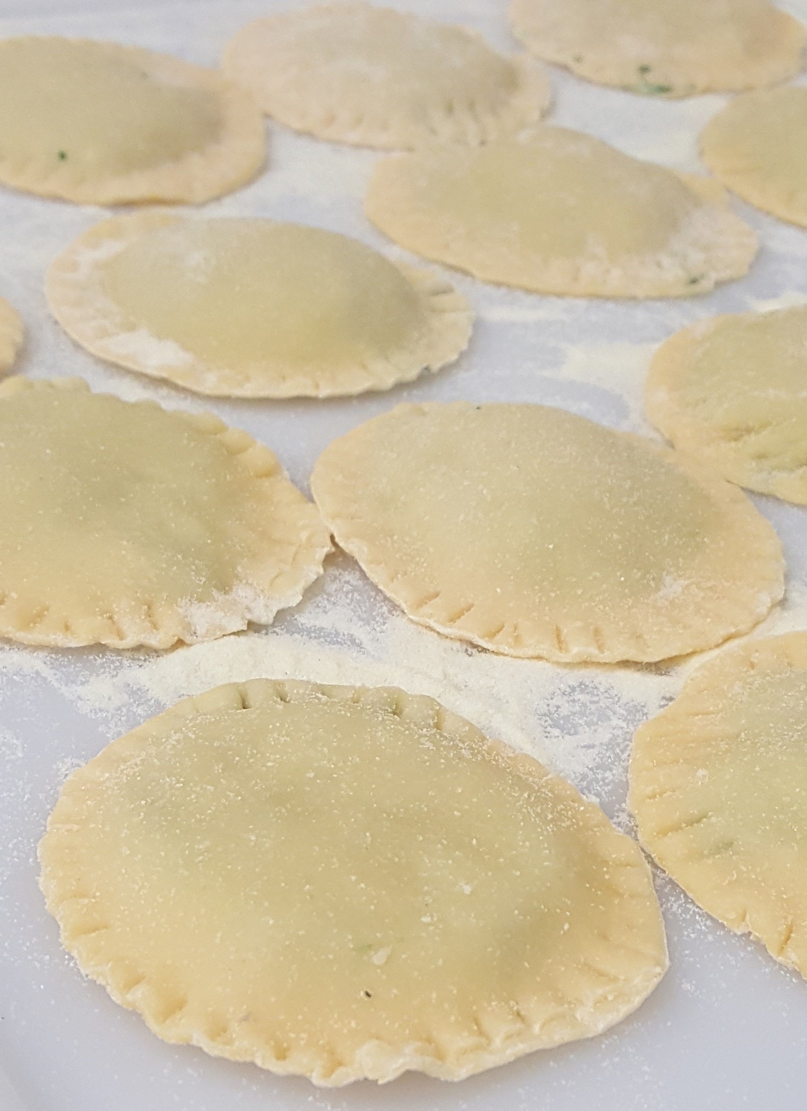 Several round, unfilled pastry doughs on a surface with flour.