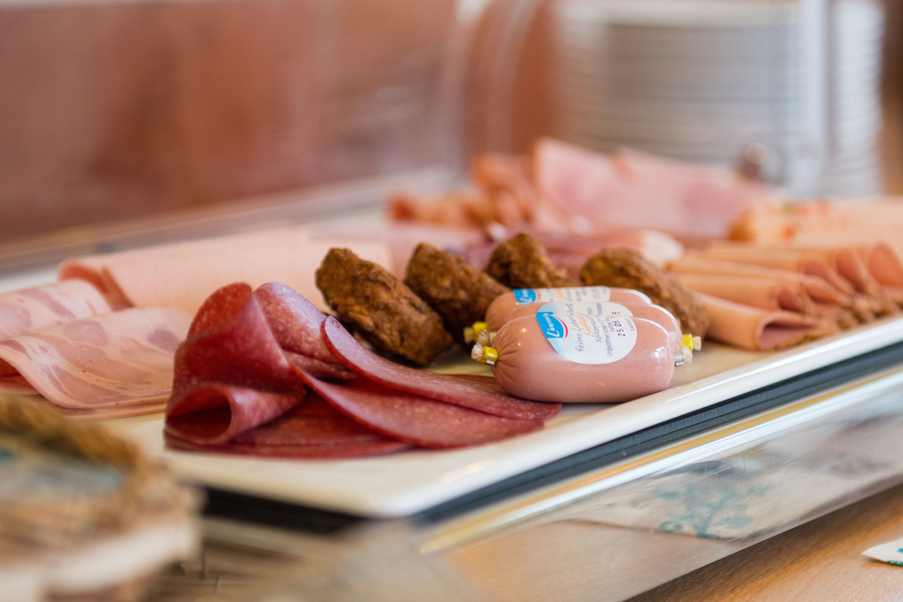 A charcuterie board with various meats and a packaged sausage.