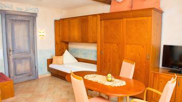 A cozy room with a wooden bed, a sofa, a dining table with chairs, and a television.
