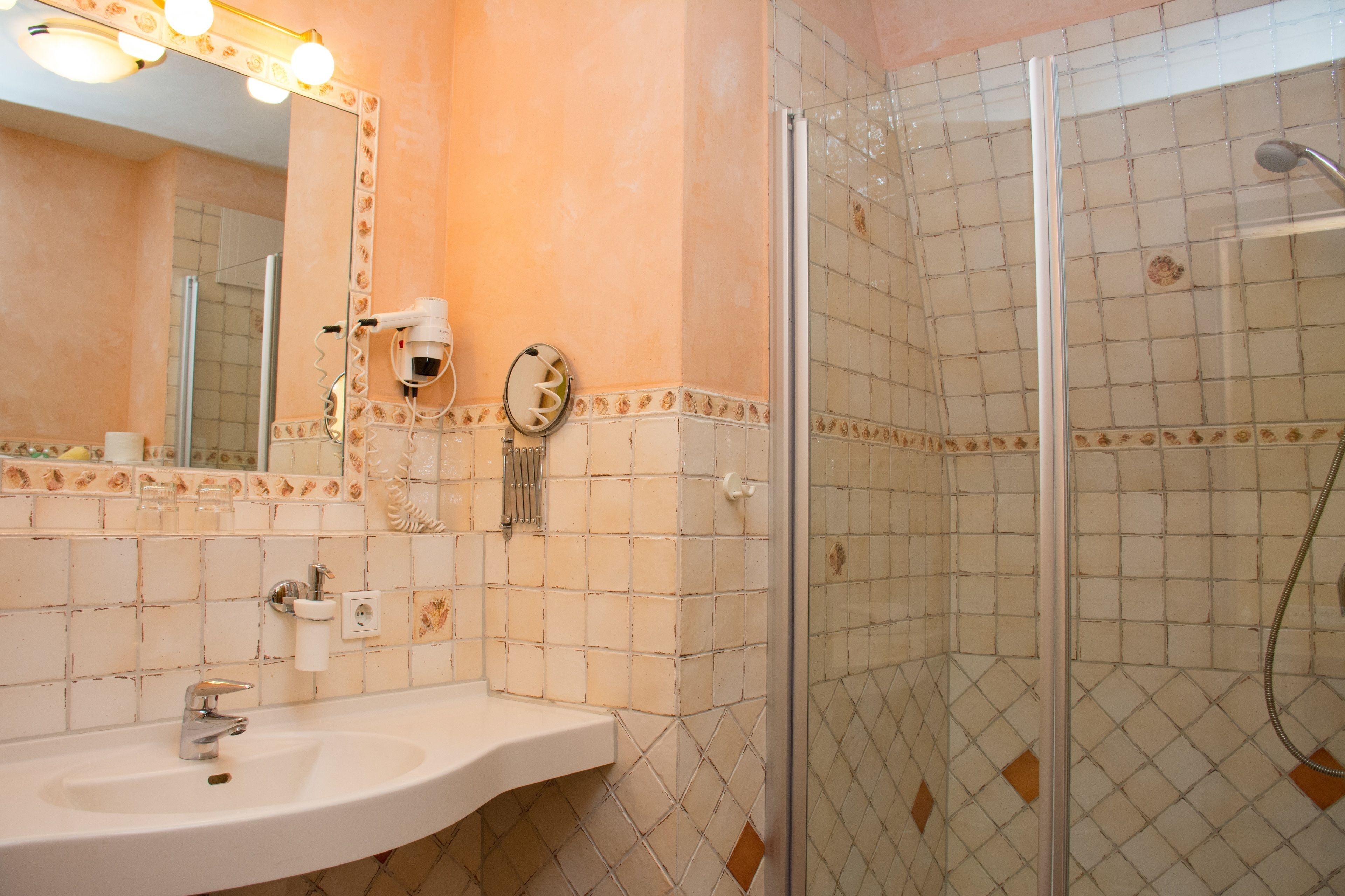 Een badkamer met een wastafel, spiegel en douche.