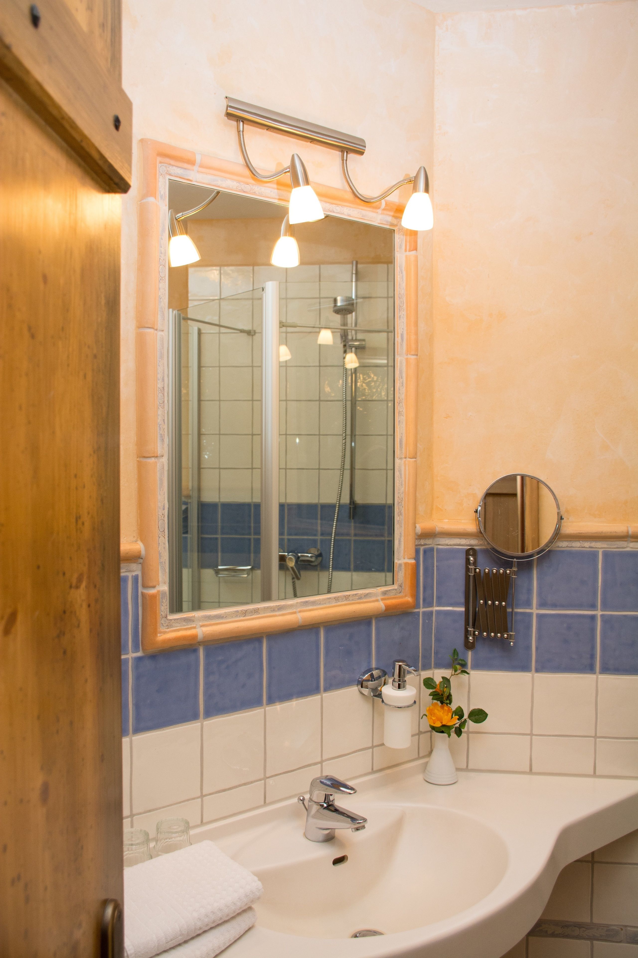A bathroom with a sink, mirror, and shower.