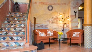 Un escalier orné de carreaux colorés, un ensemble de meubles de salon, une table avec des fleurs et une horloge murale.
