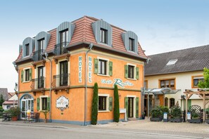 Ett hotell i två våningar med balkonger, en skylt med texten ”HOTEL casa Rustica” och utomhusplatser för sittande.