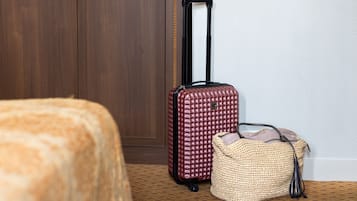 A room with a wooden wardrobe, a red suitcase, and a woven bag.