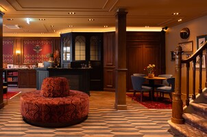 Un hall d’hôtel avec un pouf rond, un coin bar et un escalier.