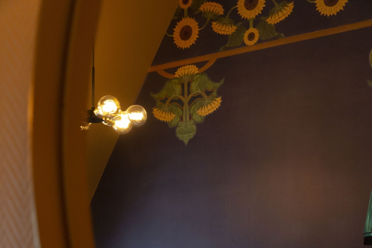 Un dormitorio con una cama, cabecera y pared con diseño floral.