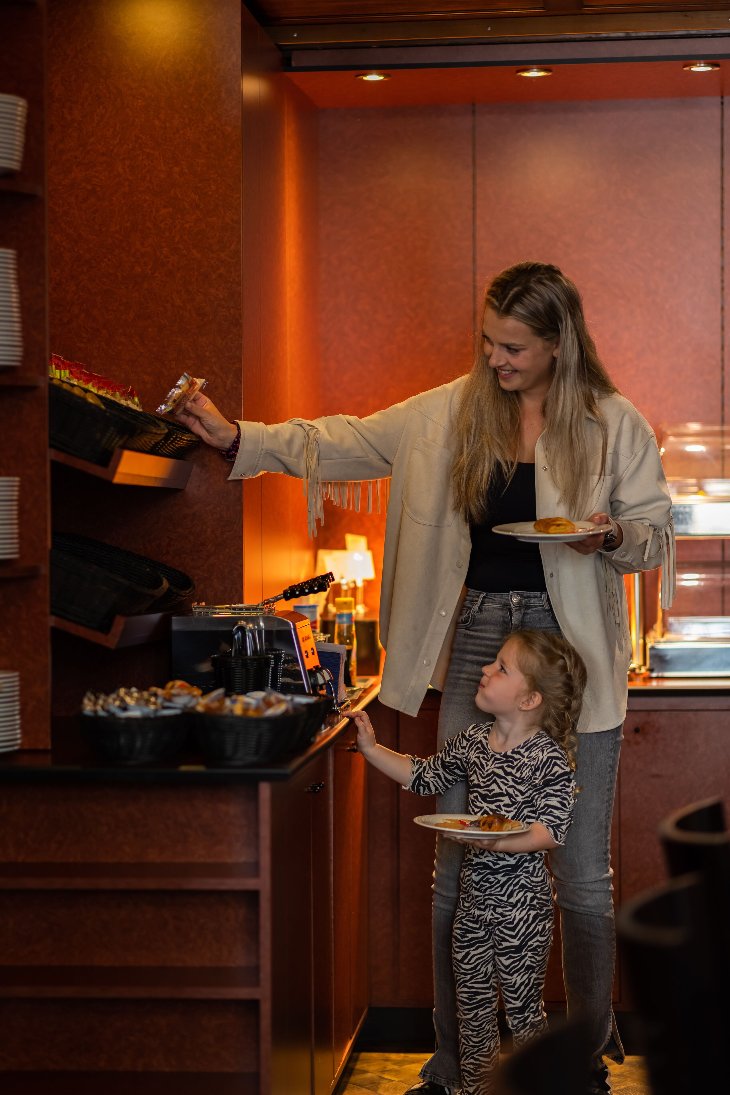 Un espace buffet avec un comptoir, où un enfant reçoit de la nourriture d’un adulte.