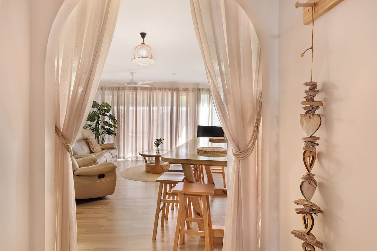 A dining area with a wooden table, benches, and a ceiling fan.
