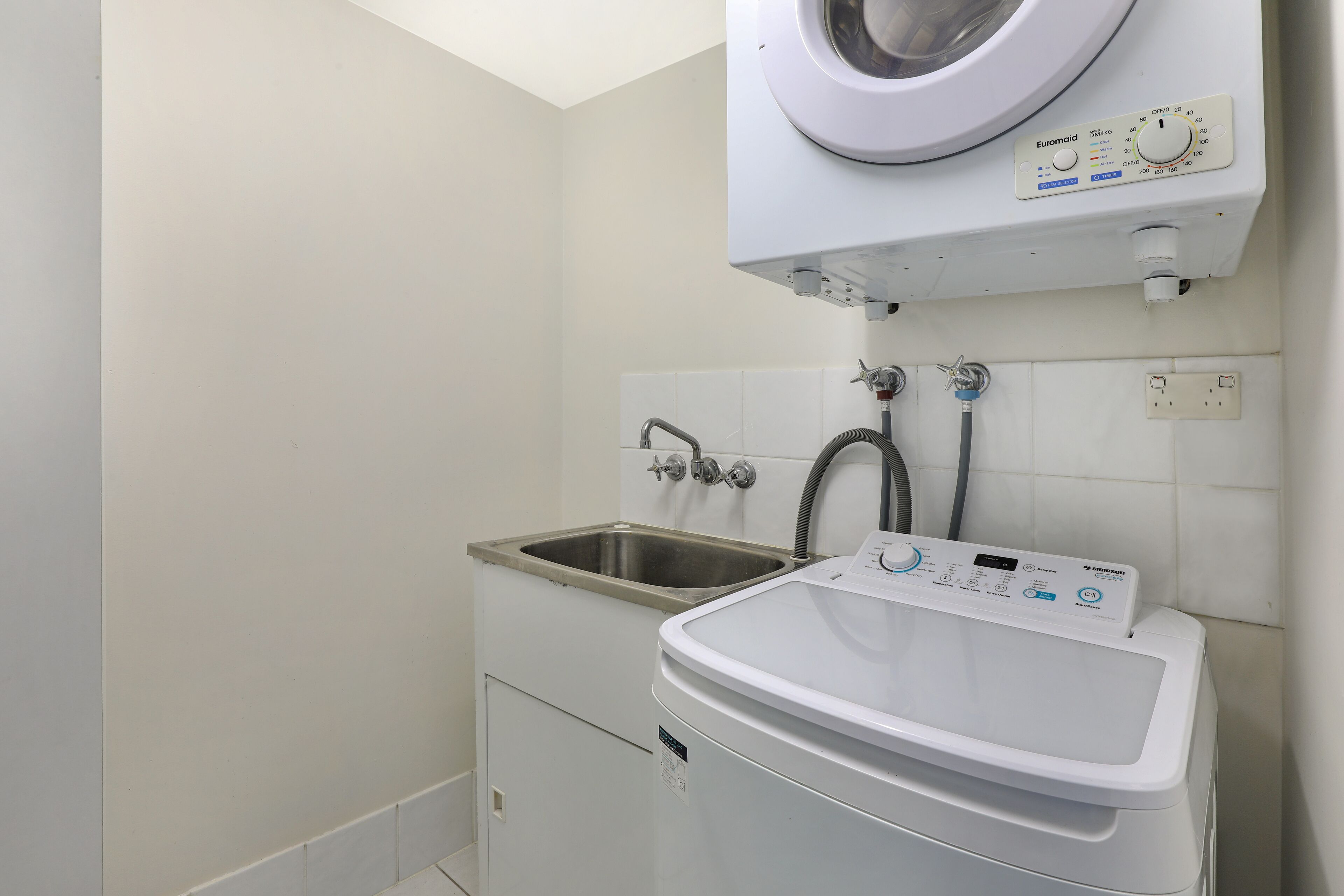 A laundry area with a washing machine, a sink, and a hose.