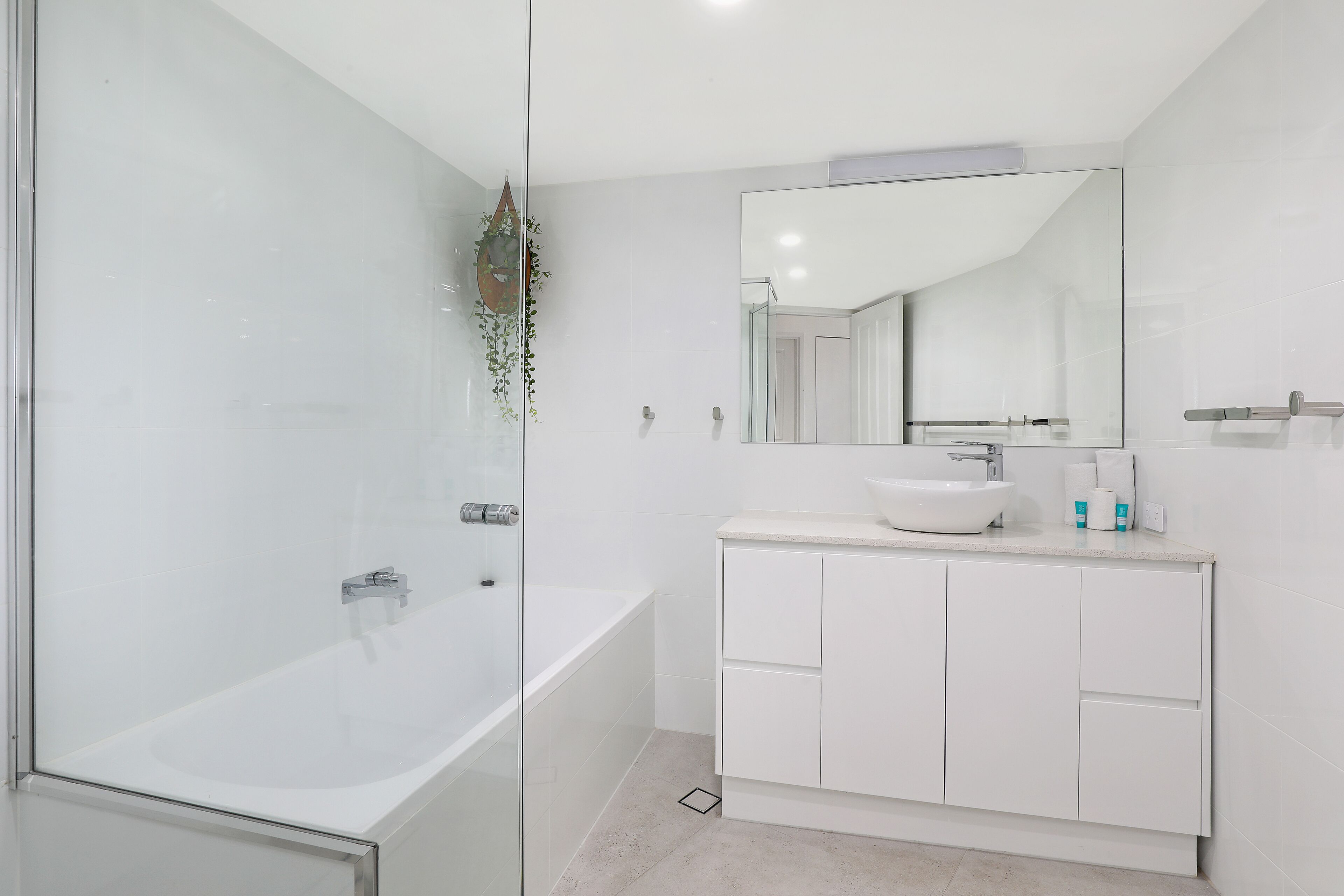 Une salle de bain moderne avec une douche à parois de verre, une baignoire blanche et un meuble-lavabo avec un miroir.