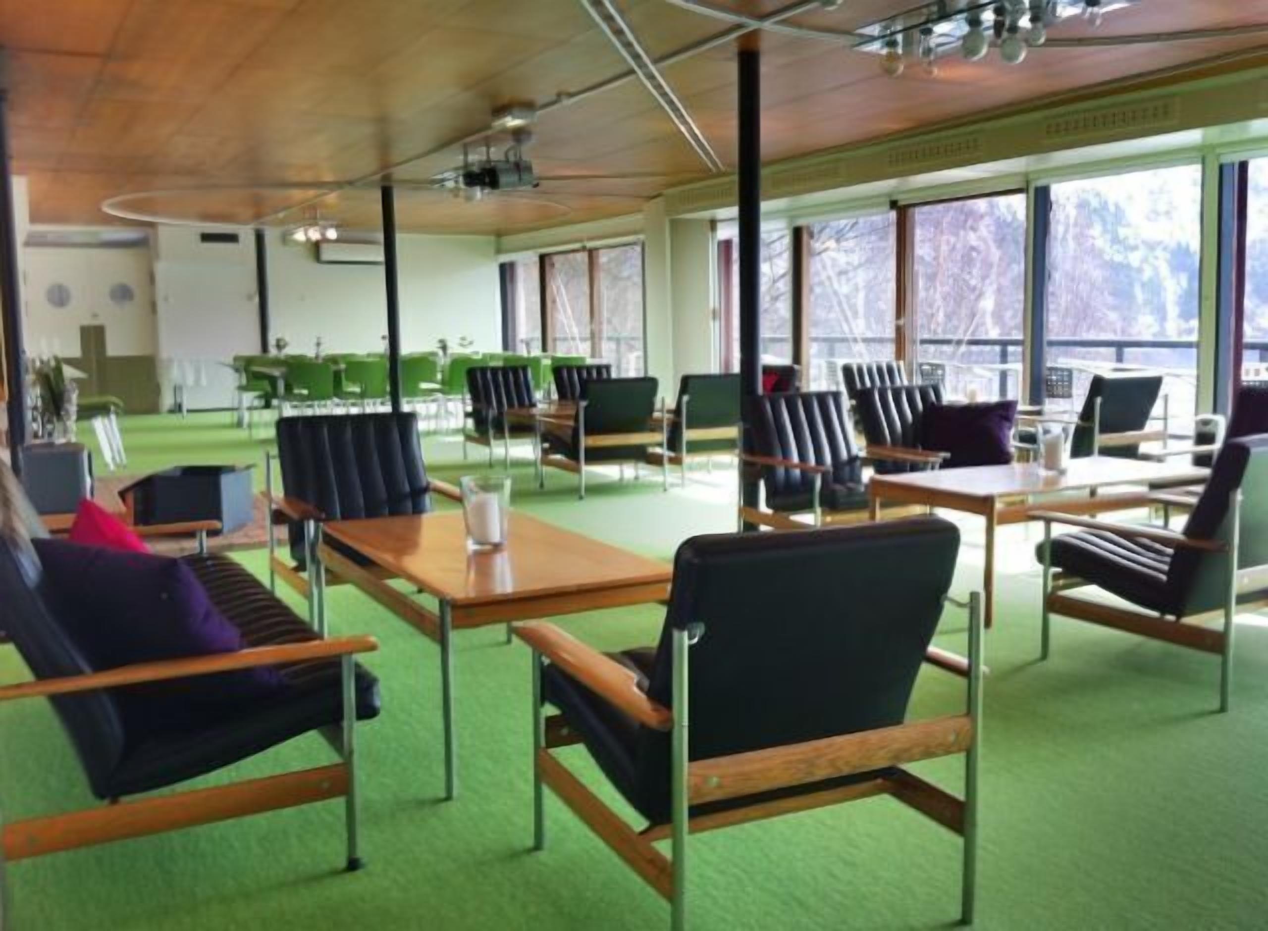 A modern conference room with green carpeting, black and brown chairs, and a wooden table.