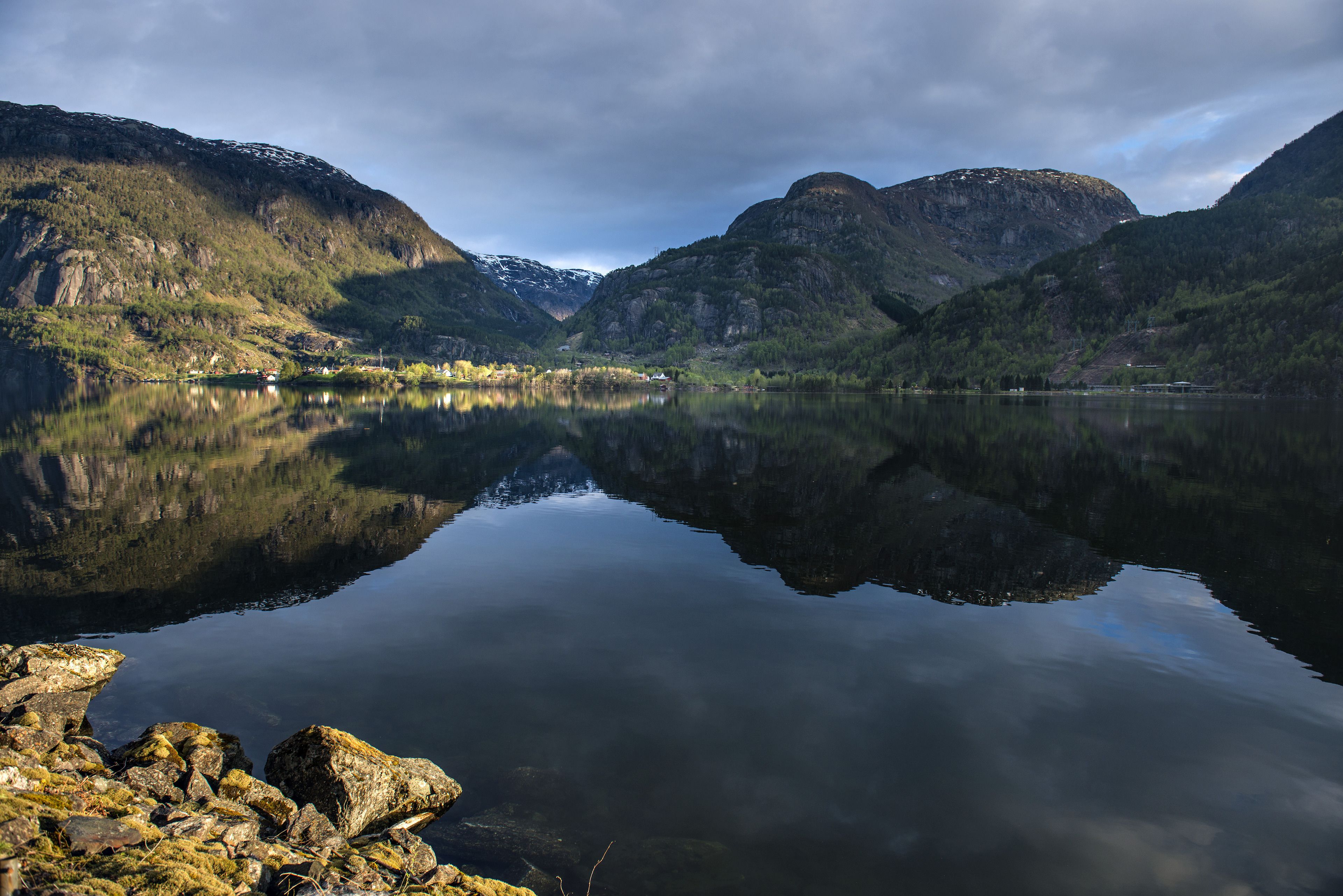 A calm lake with mountains in the background and a clear reflection of the sky.