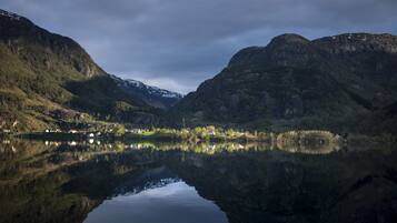 A serene lake with reflections of surrounding mountains and a small settlement.