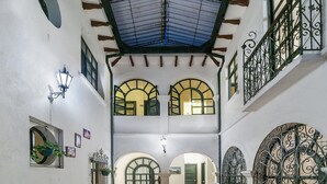 A spacious atrium with high ceilings, arched windows, and ornate iron railings. - Hotel La Herreria Colonial (Popayán)