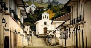 A narrow street leading to a white church with a bell tower, surrounded by buildings with balconies and windows. - Hotel La Herreria Colonial (Popayán)