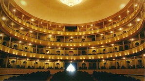 A multi-tiered auditorium with tiered seating and a central stage, illuminated by chandeliers. - Hotel La Herreria Colonial (Popayán)