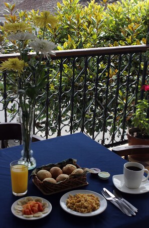 A table set with breakfast items, a vase with flowers, and a view of greenery. - Hotel La Herreria Colonial (Popayán)