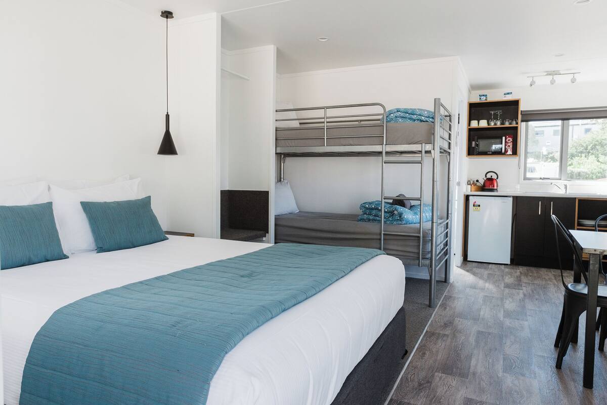 Une chambre d’hôtel moderne dotée d’un grand lit, d’un bureau, d’une kitchenette et offrant une vue sur l’extérieur.