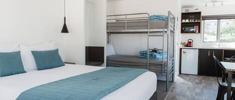 Una habitación de hotel moderna con una cama grande, un escritorio, una kitchenette y vistas al exterior.