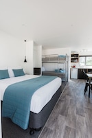 Una habitación de hotel moderna con una cama grande, un escritorio, una kitchenette y vistas al exterior.