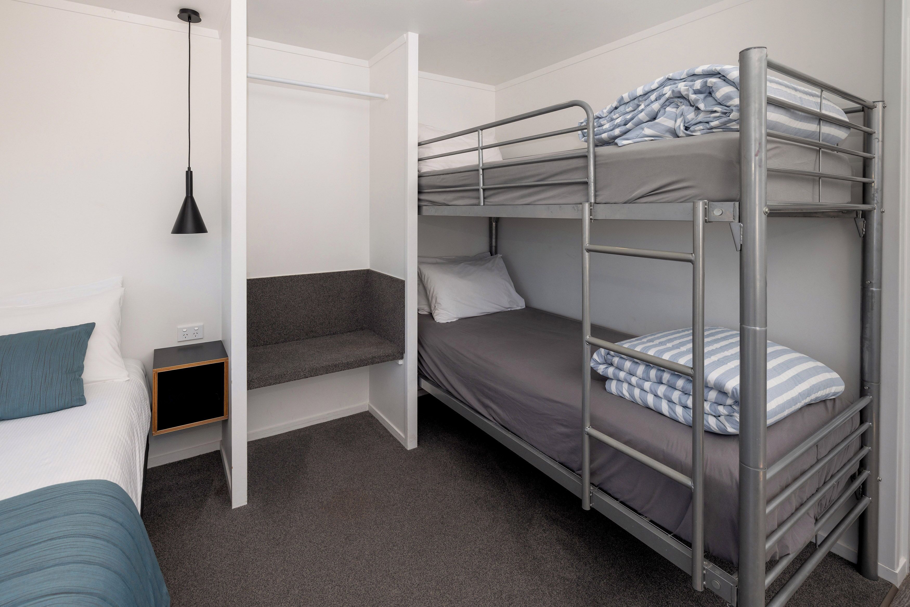 A bunk bed room with a desk and a hanging light.