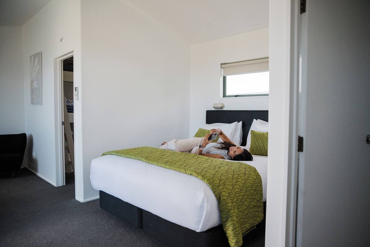 Une chambre à coucher avec un lit, une table de chevet, une fenêtre et une porte.