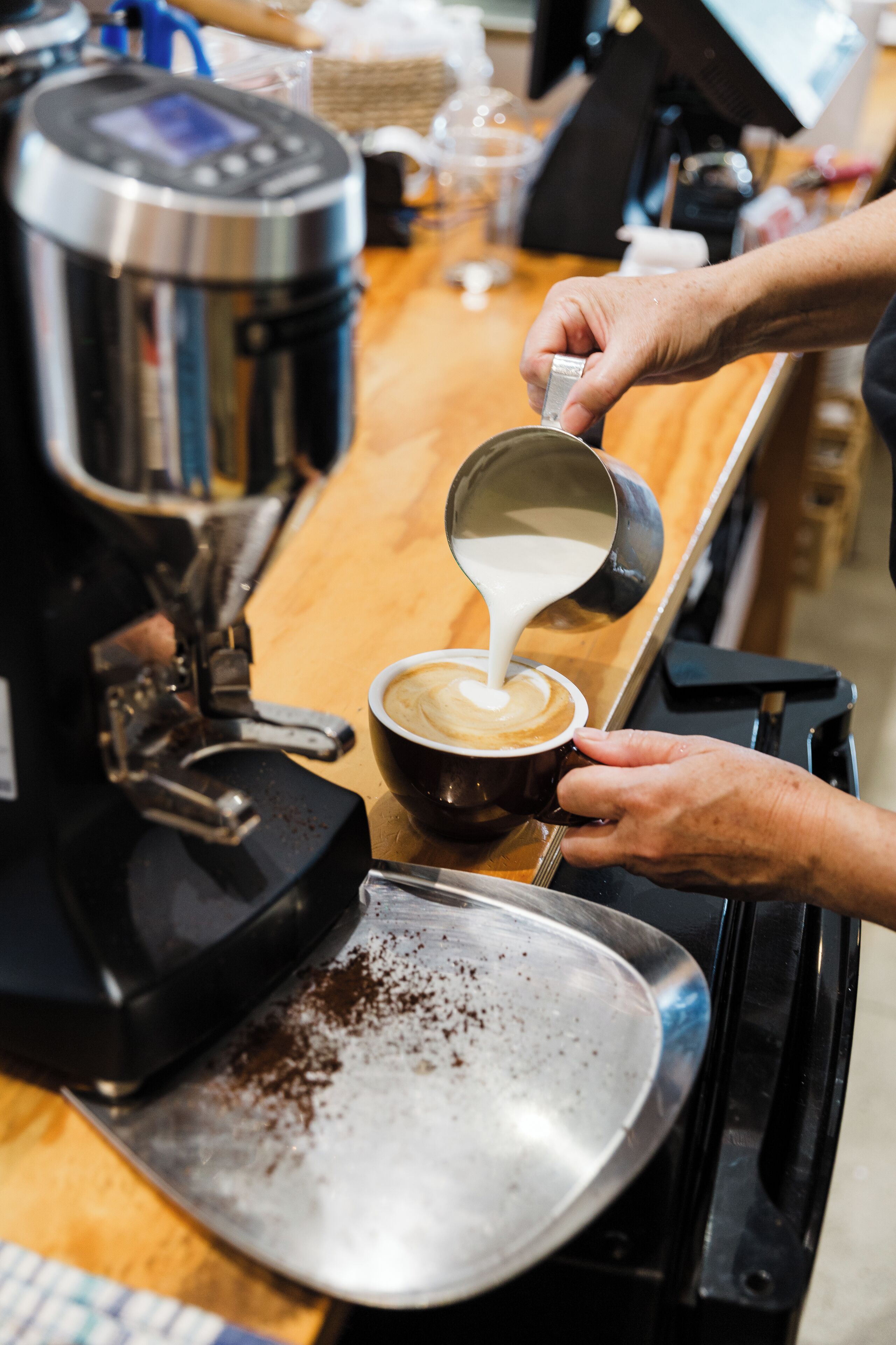 A person pouring milk into a cup of coffee.