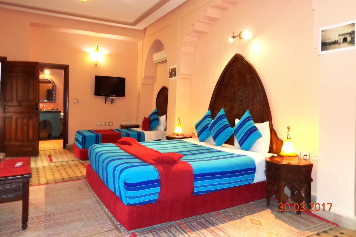 A hotel room with a large bed, a television, and a small table.