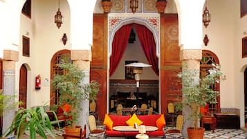 Un patio con una fuente, sofá rojo y plantas en macetas.