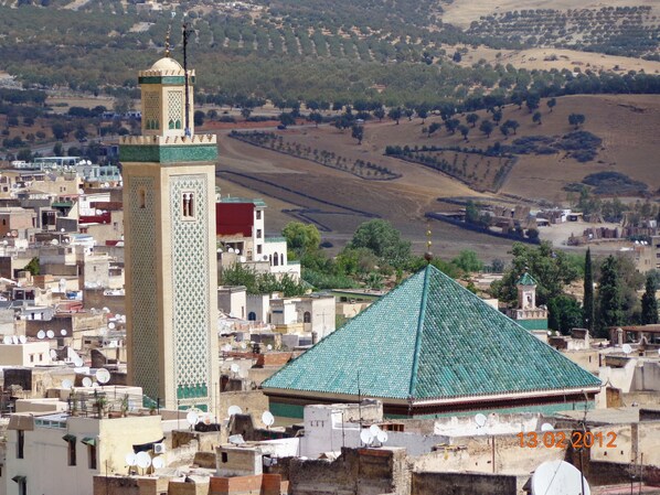 A densely packed urban area with traditional architecture, including a prominent tower and a building with a green-tiled roof.