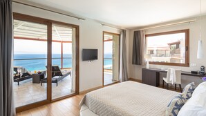 A hotel room with a large bed, a desk, and a view of the sea. - Blue Bay Halkidiki “Adults Only ” (Kassandra)