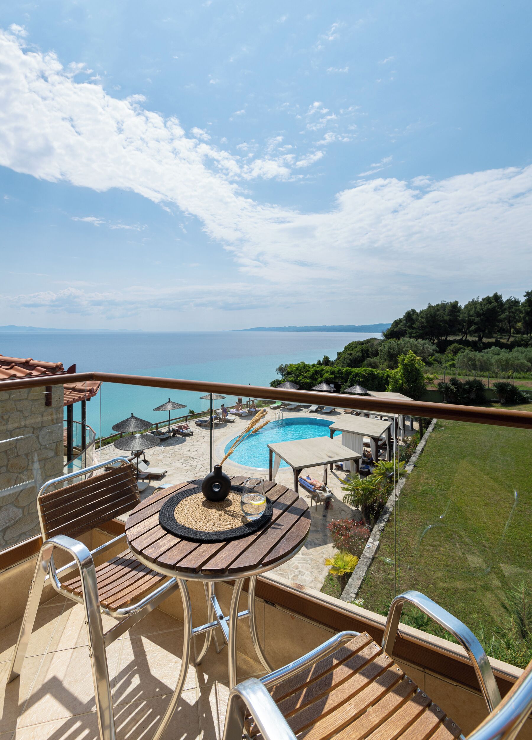 A balcony with a view of a swimming pool, lounge chairs, and umbrellas.