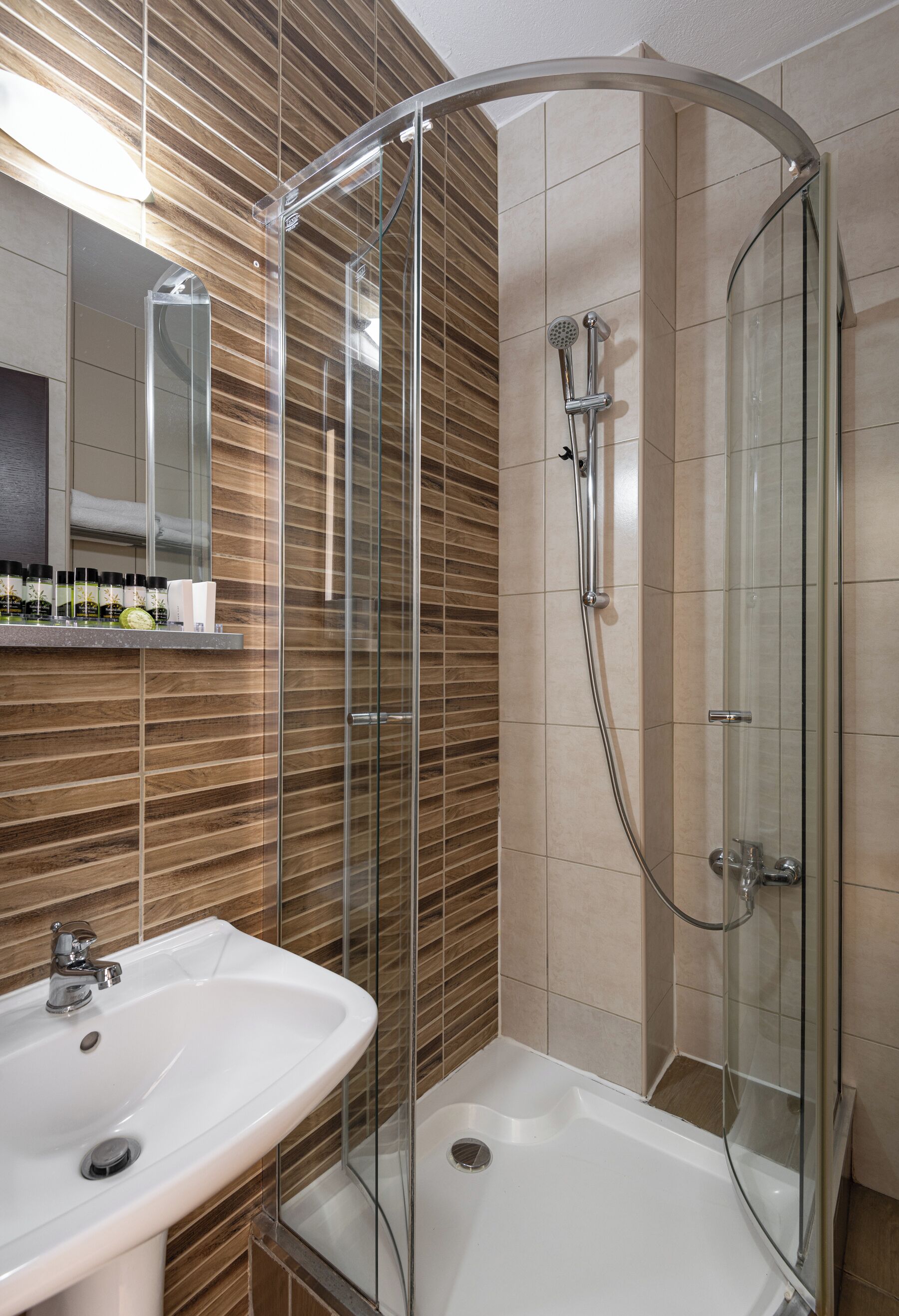 A modern bathroom with a glass-enclosed shower, a white sink, and a mirror above the sink.